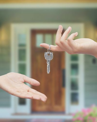 Mani con chiavi sfondo porta di casa